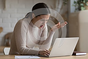 Concerned girl staring at laptop screen with angry face