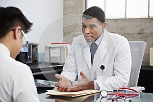 Concerned mixed race male doctor counselling male patient