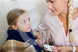 Concerned mother giving pills to daughter with fever
