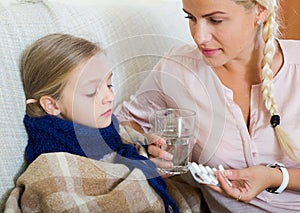 Concerned mother giving pills to daughter with fever