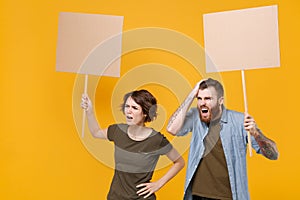 Concerned protesting young two people guy girl hold protest signs broadsheet blank placard on stick looking aside