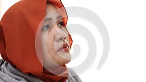 Concerned sad Asian muslim woman looking up, thinking something with blank stare, over white background