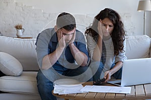 Concerned upset millennial couple counting overspent budget