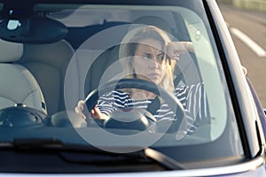Concerned woman on driver seat of car not driving look through windshield thinking of money crisis