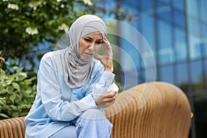 Concerned woman in hijab feeling unwell outdoors