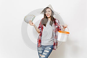 Concerned woman in newspaper hat holding bundle of dollars, cash money and empty paint bucket with copy space isolated
