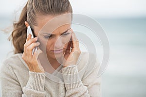 Concerned woman talking cell phone on beach