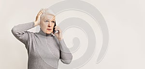 Concerned woman talking on phone, holding hand on head