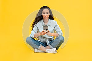 Concerned Woman Using Cellphone Frowning Texting Sitting Over Yellow Background