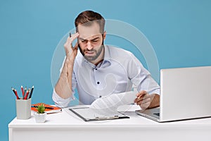 Concerned young man in shirt work at desk with pc laptop isolated on pastel blue background. Achievement business career