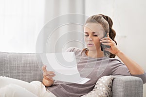 Concerned young woman with letter and talking cell phone