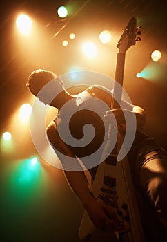 Concert, band and guitar with man on stage for music, performance and rock show. Event, spotlight and energy with male