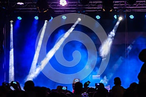 Concert crowd attending a concert, people silhouettes are visible, backlit by stage green lights. Smart phones are visible here an