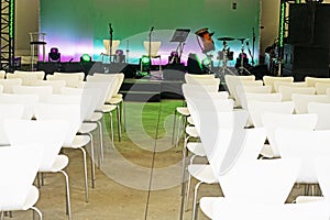 concert music stage before performance with white chairs.
