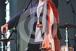 Concert view of a contrabass violoncello player with vocalist and musical rock band during jazz orchestra band performing music,