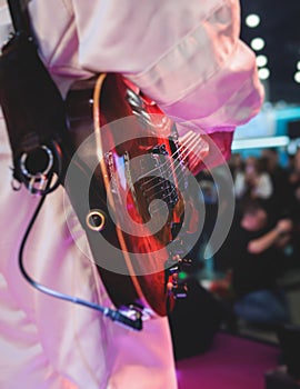 Concert view of an electric guitar player with vocalist and rock band performing in a club, male musician guitarist on stage with