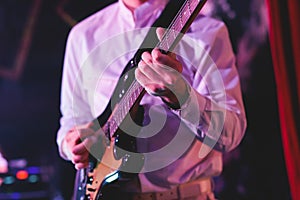 Concert view of an electric guitar player with vocalist and rock band performing in a club, male musician guitarist on stage with