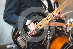 Concert view of a musician, electric bass guitar player with during band performing rock music,  bassist player on stage