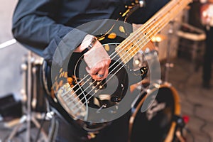 Concert view of a musician, electric bass guitar player with during band performing rock music,  bassist player on stage