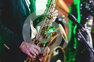 Concert view of a saxophone player with vocalist and musical jazz band in the background