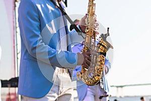 Concert view of saxophonist in a blue and white suit, a saxophone sax player with vocalist and musical band during jazz orchestra