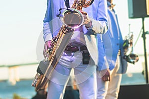 Concert view of saxophonist in a blue and white suit, a saxophone sax player with vocalist and musical band during jazz orchestra