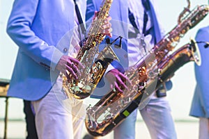 Concert view of saxophonist in a blue and white suit, a saxophone sax player with vocalist and musical band during jazz orchestra