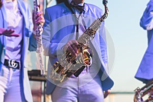 Concert view of saxophonist in a blue and white suit, a saxophone sax player with vocalist and musical band during jazz orchestra