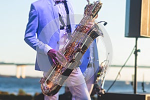 Concert view of saxophonist in a blue and white suit, a saxophone sax player with vocalist and musical band during jazz orchestra