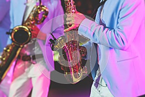 Concert view of saxophonist, a saxophone sax player with vocalist and musical band during jazz orchestra show performing music on