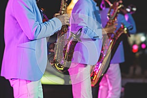 Concert view of saxophonist, a saxophone sax player with vocalist and musical band during jazz orchestra show performing music on