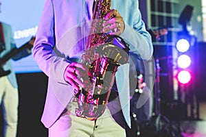 Concert view of saxophonist, a saxophone sax player with vocalist and musical band during jazz orchestra show performing music on