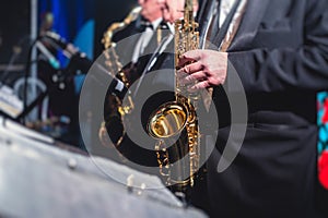 Concert view of a saxophonist, saxophone sax player with vocalist and musical during jazz orchestra performing music on stage