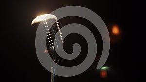 Concert vintage microphone stay on stage in empty club under white spotlight