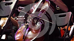 Concert, a woman musician playing the cello on stage with a lot of colleagues.