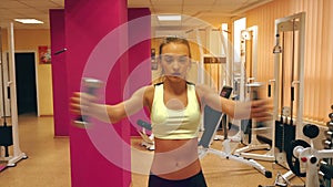 Concetrated blonde woman working hard in a gym with dumbbells