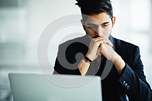 Concetrated indian man smiling and working at office