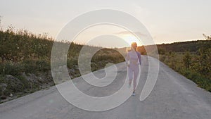 Concetrated young lady runs on the road in tracksuit