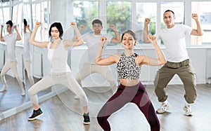 Concetrated young people studying movement of contemporary dance in classroom