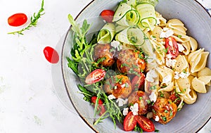 Conchiglie with meatballs, feta cheese and salad on light background.