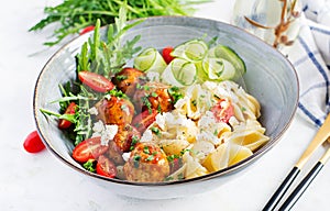 Conchiglie with meatballs, feta cheese and salad on light background.