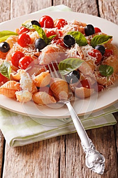 Conchiglie pasta with tomatoes, olives and parmesan cheese close