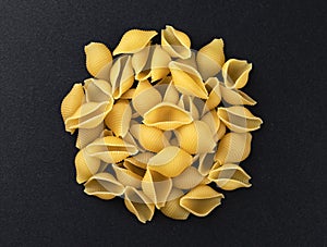 Conchiglie rigate. Raw striped shell pasta on black background, top view