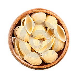Conchiglie rigate, shell shaped and furrowed Italian pasta in a wooden bowl photo