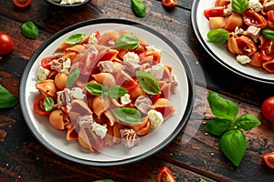 Conchiglie Tuna pasta with tomato sauce, feta cheese and basil on wooden table. healthy food