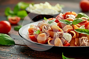 Conchiglie Tuna pasta with tomato sauce, feta cheese and basil on wooden table. healthy food