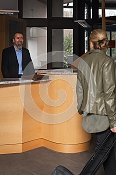 Concierge in a hotel is smilling to an female guest