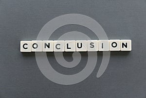 Conclusion word made of square letter word on grey background. photo