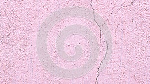 Concrete background. Pink old cracked stucco wall. Raised abstract texture. Damaged facade of building. Scuffed stone surface in