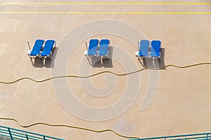 Concrete beach with tree couple of blue deck chairs under the sun light, Madeira island, Portugal